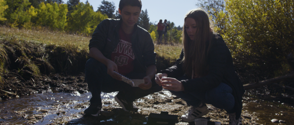 students on bank of mountain stream